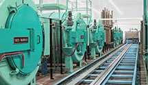 Photo of custom nitrocarburizing system consisting of 6 retort furnaces and automatic handling track used for processing 1,000,000 gears per year.